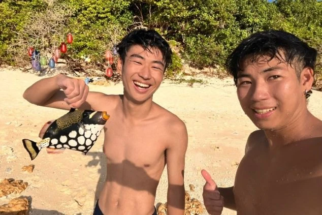 砂浜でポージングするリゾートバイトスタッフ。休日の風景。