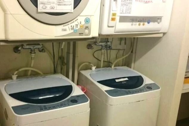 寮のランドリースペース。複数台の全自動洗濯機と衣類乾燥機が上下に設置されています。