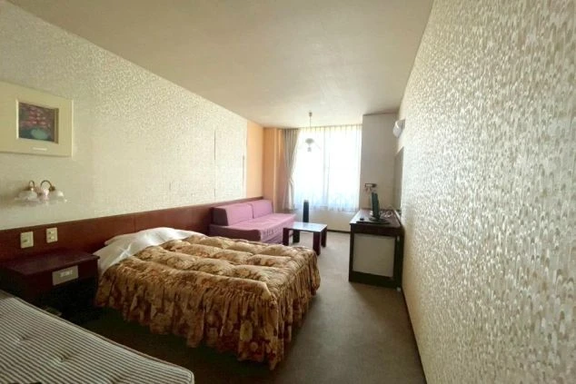 布団が敷かれたベッド、ソファ、テレビ、ミニテーブルが備わった広い個室寮