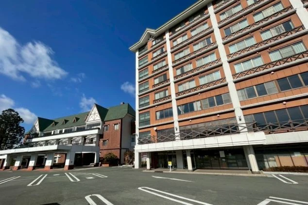 青空の下に建つ、オレンジと白の外壁が特徴的なホテルの建物外観と広々とした駐車場