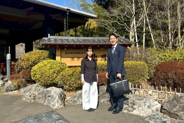 ホテルの前で笑顔を見せるワクトリの営業とリゾートバイトスタッフさんの写真。