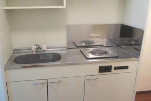 シンクとIHヒーターまたは電気コンロが設置された、寮室内に備え付けのミニキッチンの画像