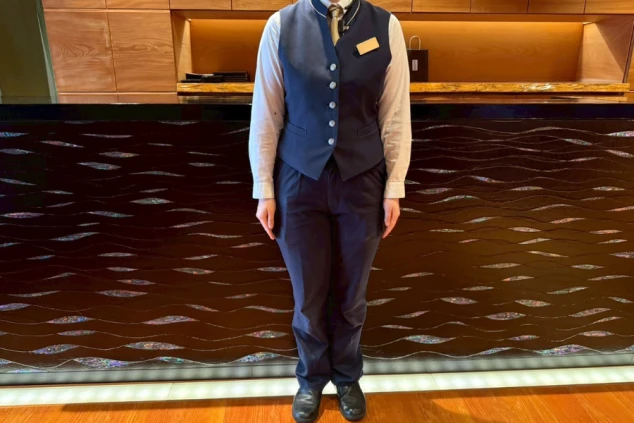 レストランスタッフの制服。紺のベストにネクタイ、スラックスのフォーマルな装い。