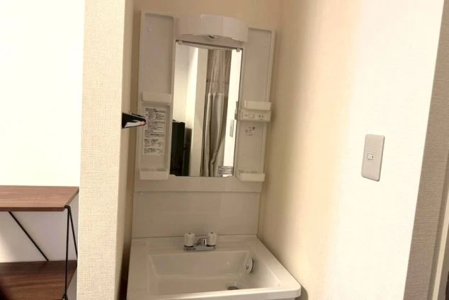 鏡とコンセントが備わった白い洗面台。