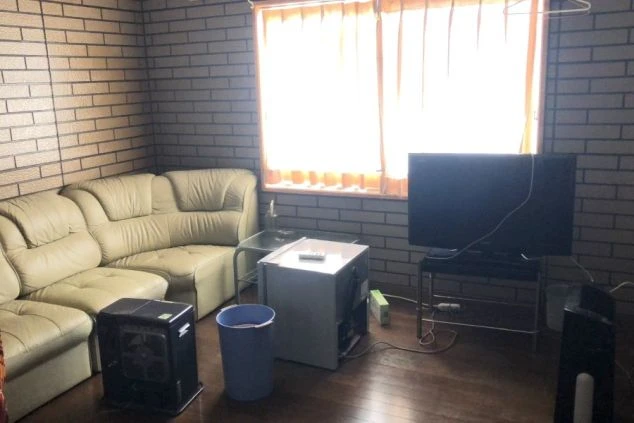 リゾートバイト個室寮の室内。L字ソファやテレビ、暖房が完備された、仕事終わりもゆっくり寛げる空間。