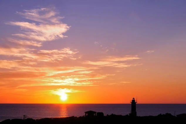 北海道の利尻島や礼文島などの離島エリアで、水平線に沈む夕日が空と海をオレンジ色に染める美しい夕景の画像。