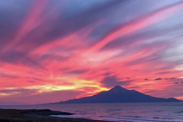 北海道の離島・利尻島で、夕暮れ時の空が鮮やかなピンクと紫のグラデーションに染まり、海上に「利尻富士（利尻山）」がシルエットとして浮かび上がる幻想的な風景の画像。