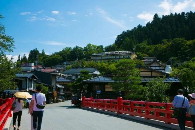 観光客で賑わう赤い橋と古い町並み。リゾートバイトの合間に地域の歴史や文化に触れる