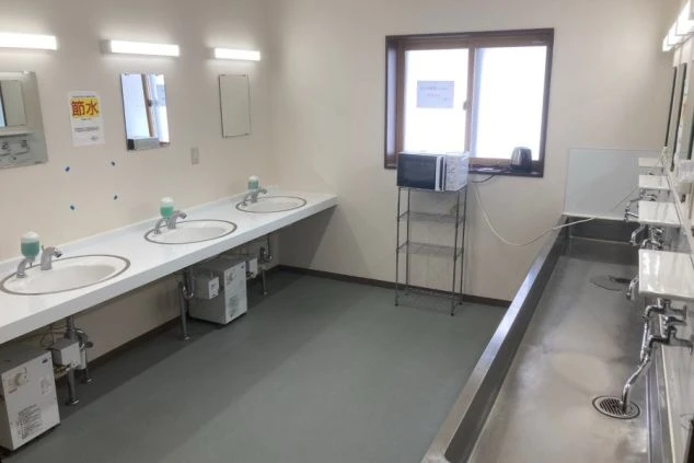 リゾートバイト寮の清潔な共用洗面所。電子レンジやケトルも設置され、自炊や身支度に便利な共用スペース。