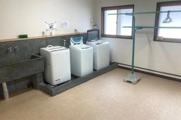 リゾートバイト寮の洗濯機と物干しスペース。冬場でも自室内や共用部でスムーズに洗濯ができる便利な環境。