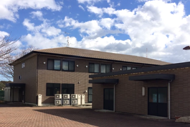 リゾートバイトの寮の建物外観。茶色い壁の2階建ての建物の写真。