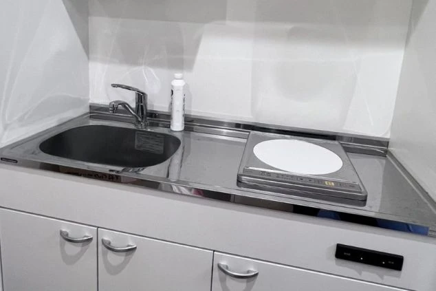 シンクとIHコンロが備わった、コンパクトで清潔なリゾートバイトの寮のミニキッチンの画像。自炊可能な環境であることをアピール。