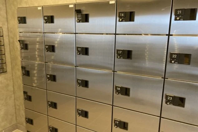 ダイヤルロック式の数字が書かれた金属製のロッカーが並ぶ。リゾートバイトの集合寮に設置された鍵付きロッカーの画像。