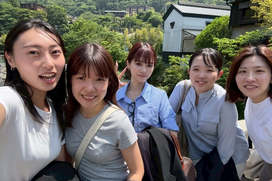 箱根の緑豊かな背景の屋外で、楽しそうに笑っている5人の若い女性たち。